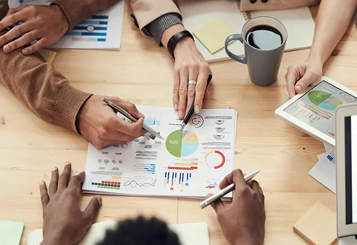 Personnes en réunion analysant un tableau de bord pour illustrer le focus sur la performance commerciale et l’accompagnement sur mesure